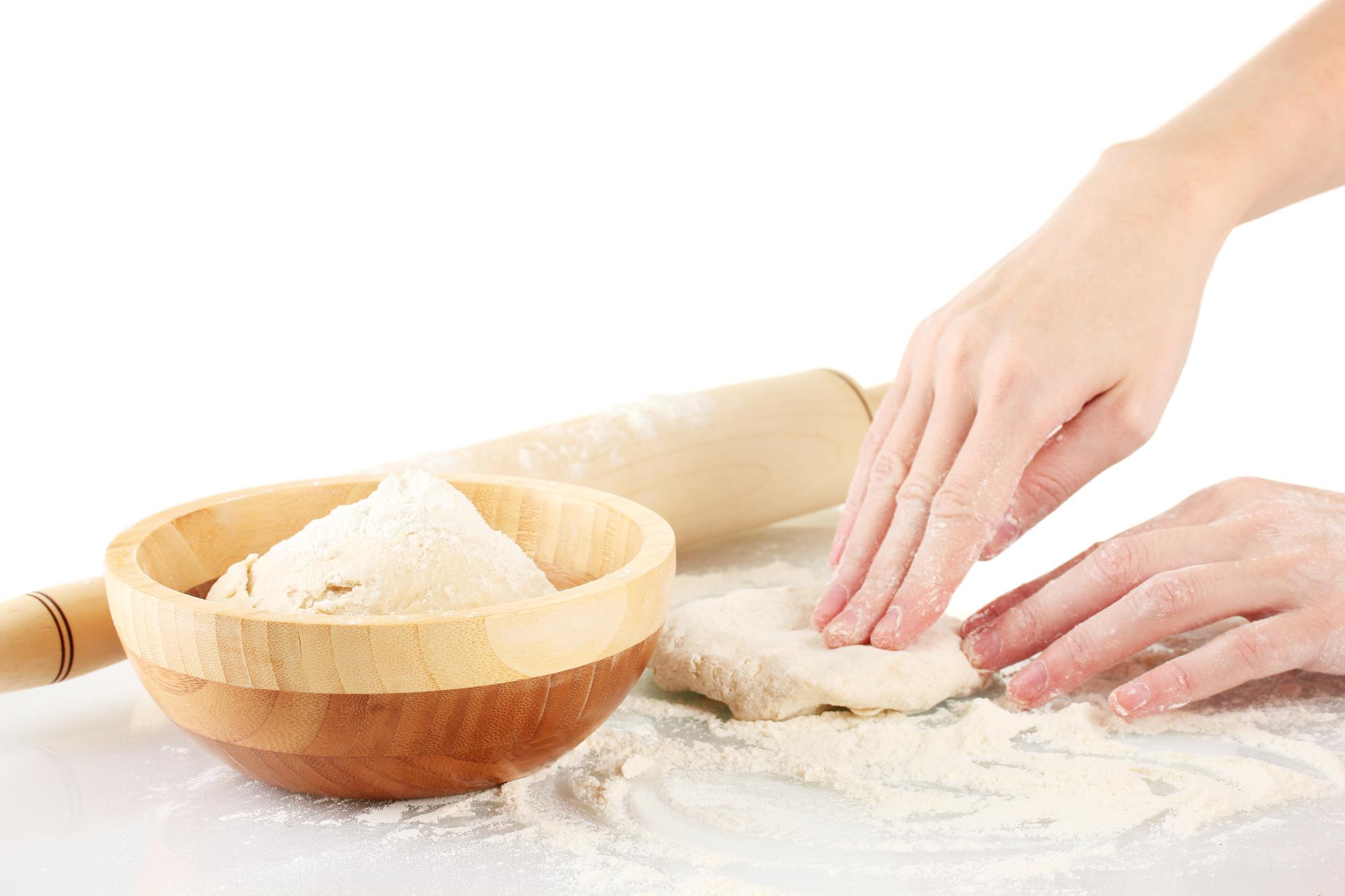 Close-up of hands kneading dough in bright studio